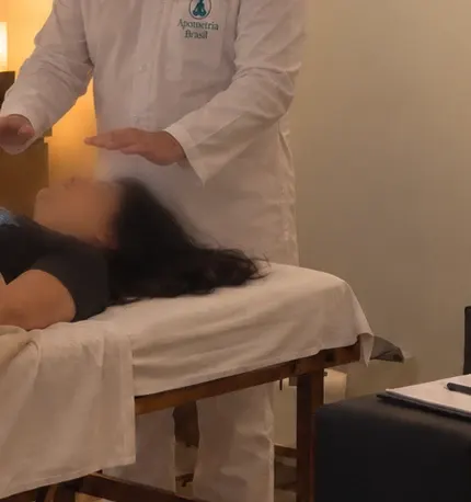Mãos do terapeuta estendidas sobre a pessoa atendida durante uma sessão de apometria na sede da Apometria Brasil